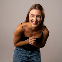 Thumbnail for Smiling woman in black top and blue jeans, showcasing happiness in a studio setting.