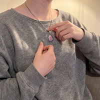 Thumbnail for Woman in a grey sweatshirt touching the silver teardrop pendant to reveal the photo | SKU: TPH-DRPN-SILVER