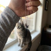 Thumbnail for Customer photo: the silver secret heart necklace with her cat's photo, her cat in the background | SKU: TPH-HRTN-SILVER