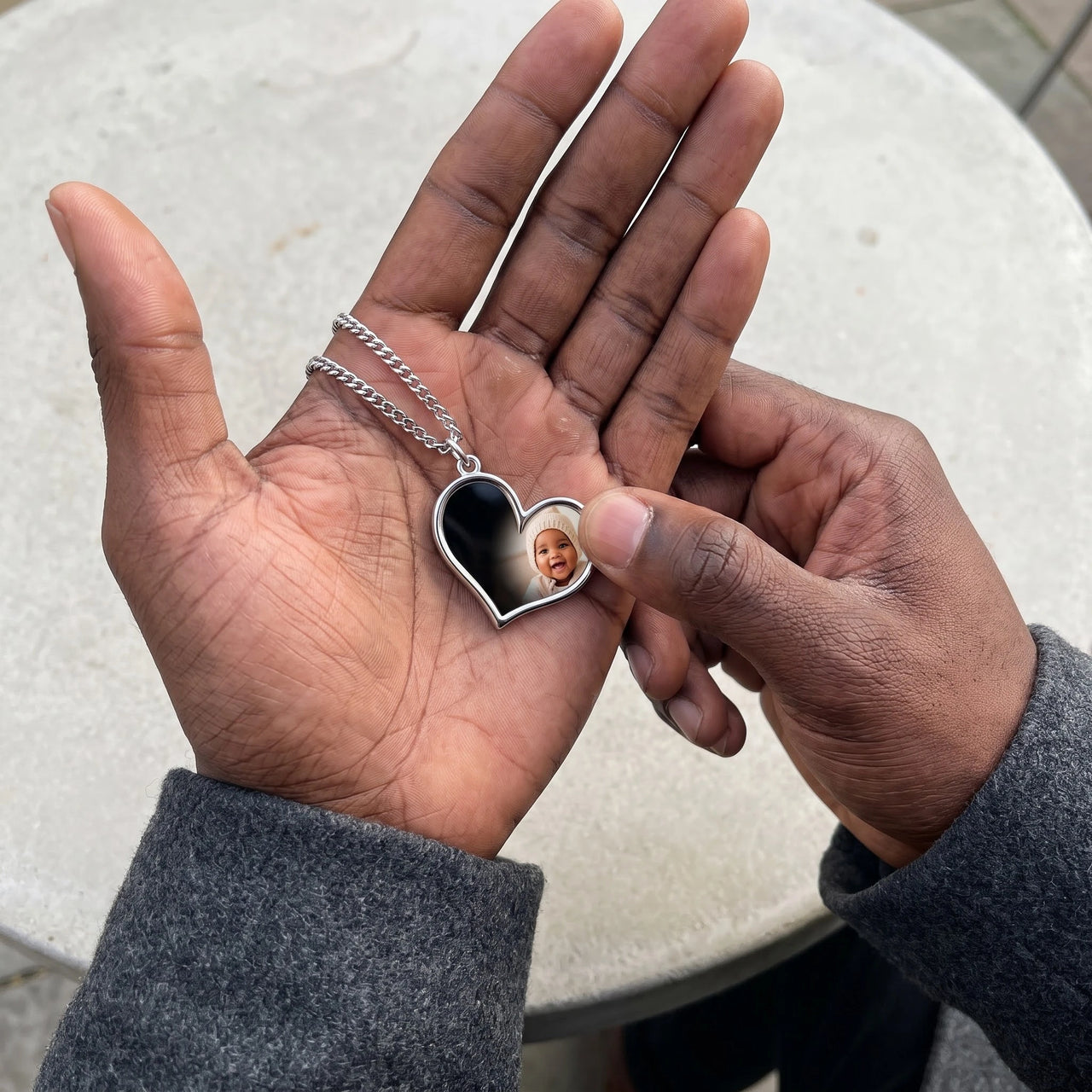 Thumb warming the silver heart pendant: the hidden photo appears under the thumb while the rest stays black | SKU: TPH-HRTN-SILVER