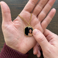 Thumbnail for Thumb warming the gold octagon pendant: the hidden photo appears under the thumb while the rest stays black | SKU: TPH-OCTN-GOLD